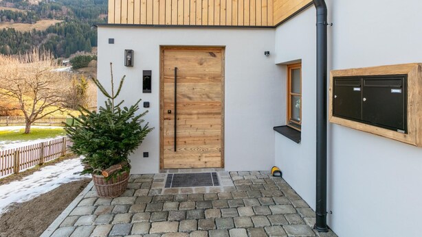 A modern building with a wooden door, a small window, and a metal mailbox. - Fantastic apartment close to the ski lift (Jochberg)