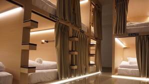 A hotel room with bunk beds, curtains, and a reflective floor. - Trybe Capsule Hostel Chiang Mai (Chiang Mai)