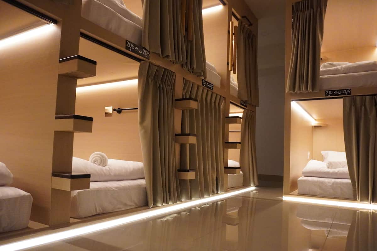 A hotel room with bunk beds, curtains, and a reflective floor.