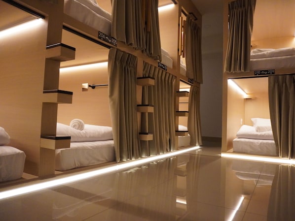 A hotel room with bunk beds, curtains, and a reflective floor.