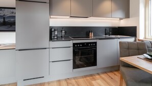A modern kitchen with grey cabinetry, a black countertop, and a built-in oven.