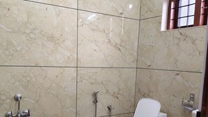 Et badeværelse med toilet, bruser og en blå spand.