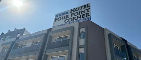 A hotel sign with the name "Hotel Four Point Corner" indicating it offers rooms and a restaurant.