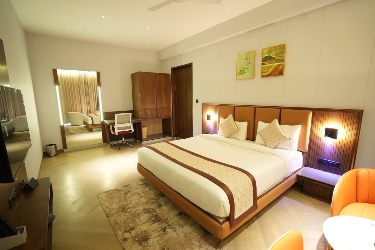 Una habitación de hotel moderna con una cama grande, un escritorio, una silla y un sofá.