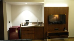 A compact kitchen with a refrigerator, sink, and a built-in microwave. - Hotel Four Point Corner (Pali)