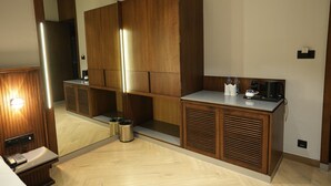 A modern bathroom with wooden cabinetry, a large mirror, a sink with a countertop, and a trash bin. - Hotel Four Point Corner (Pali)