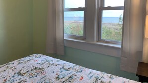 Une chambre avec un lit, une fenêtre avec des rideaux et une vue sur un plan d’eau et un pont.