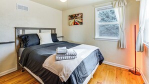 Ein Schlafzimmer mit Bett, Deckenventilator, Fenster mit Vorhängen und einem Bild an der Wand.