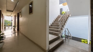 A hallway with a staircase leading to an upper level. - Hotel Admire Expressway BY ASPL (Noida)
