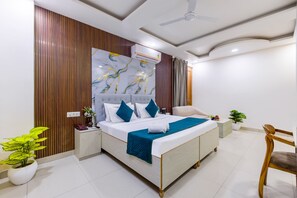 Una habitación de hotel moderna con una cama grande, un ventilador de techo, aire acondicionado de pared y una planta en maceta.