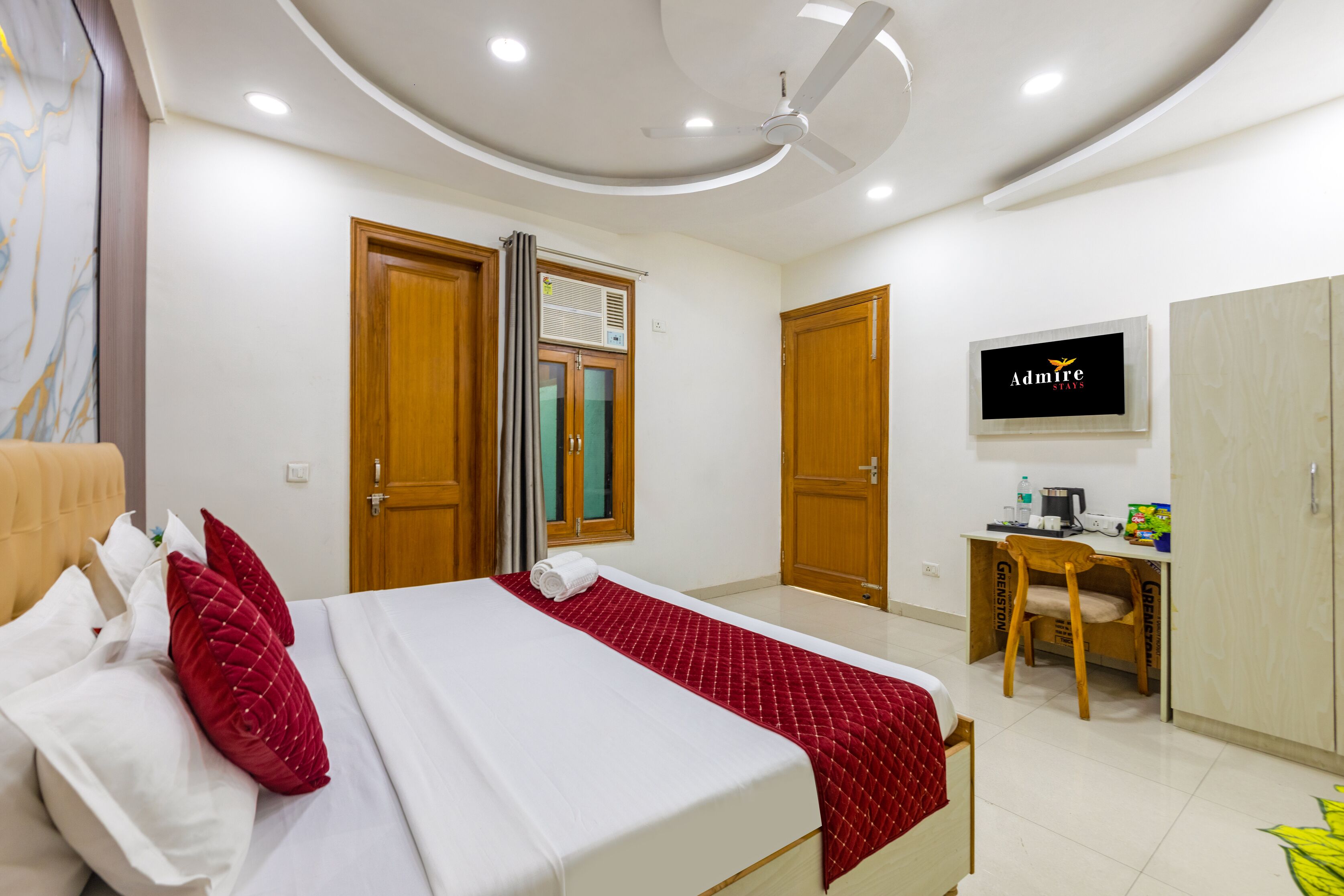 A hotel room with a bed, a desk, a chair, a TV, and a wardrobe.