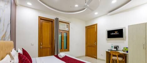 A hotel room with a bed, a desk, a chair, a TV, and a wardrobe.