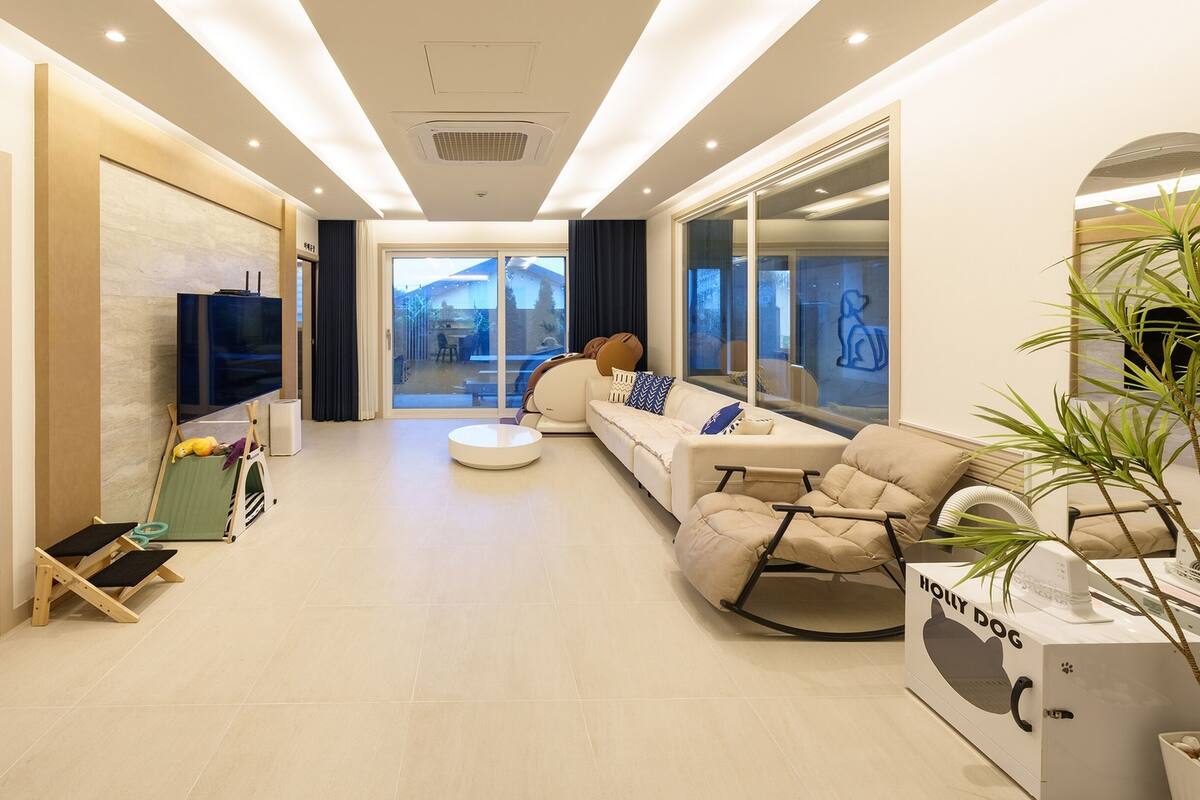 A modern living room with a sofa, a coffee table, a TV, and a large window.