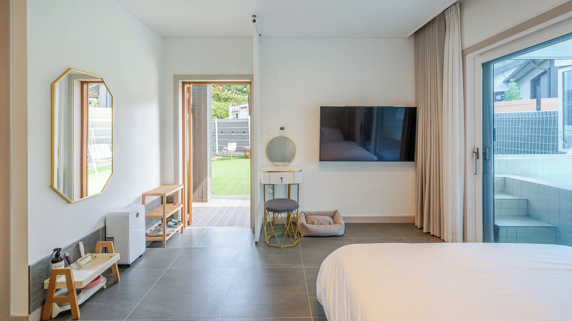 Un dormitorio moderno con una cama grande, un televisor, un espejo y vistas al exterior.