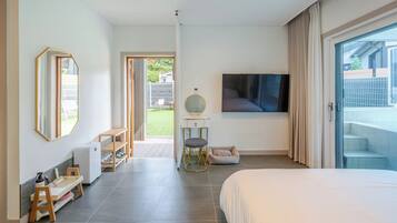 Un dormitorio moderno con una cama grande, un televisor, un espejo y vistas al exterior.