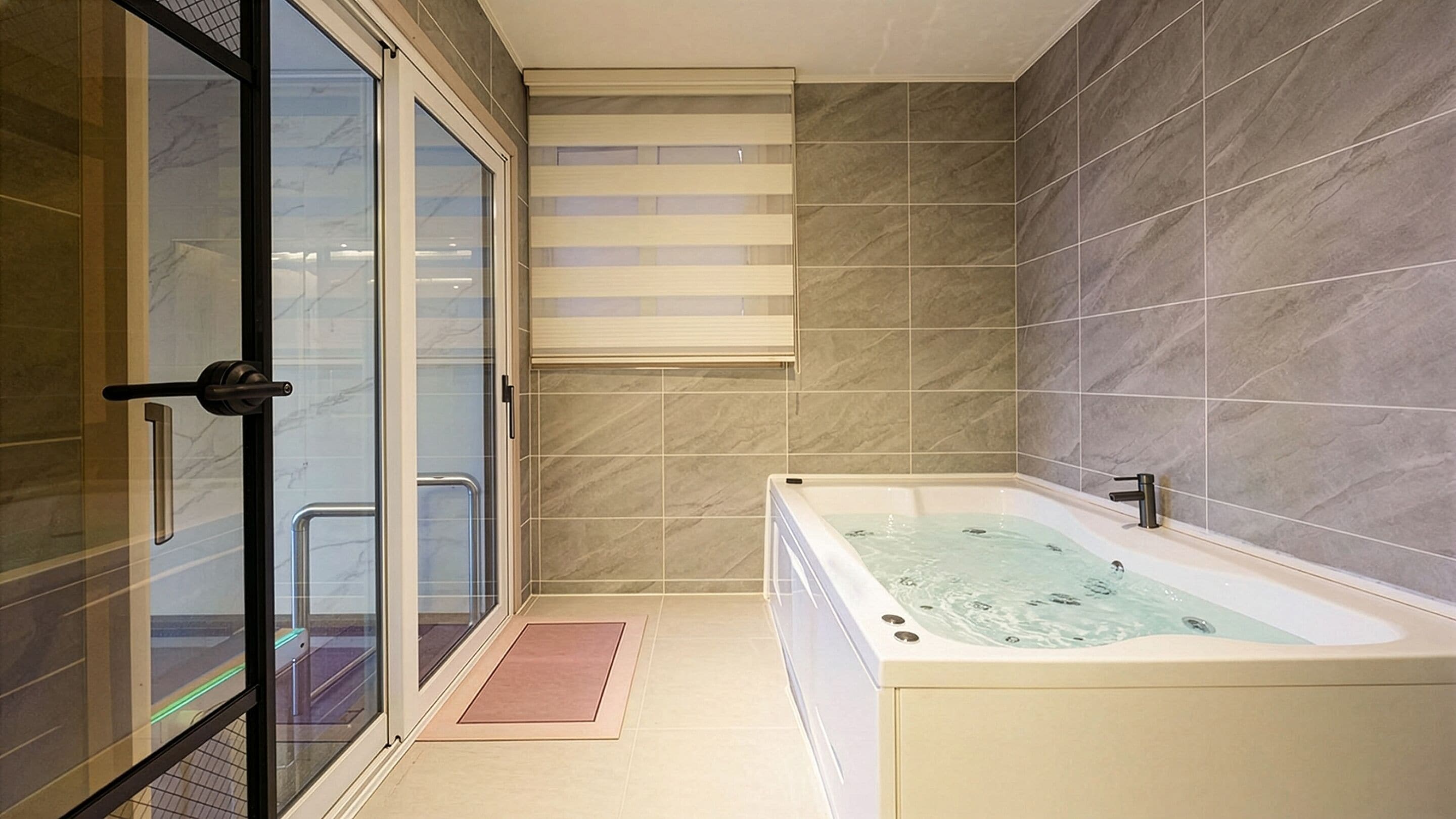 A modern bathroom with a glass shower enclosure, a bathtub, and tiled walls.