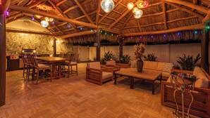 Een ruime binnenruimte met een houten plafond, een eettafel met stoelen, een bank en een decoratieve metalen standaard.
