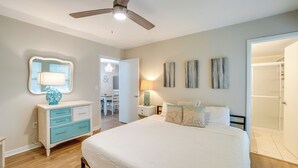 Een slaapkamer met een bed, een dressoir, een plafondventilator en een inloopkast.