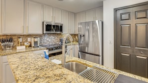 A kitchen with white cabinets, stainless steel appliances, and a granite countertop. - Modern Resort Getaway 9 Mi to Disney Parks! (Kissimmee)