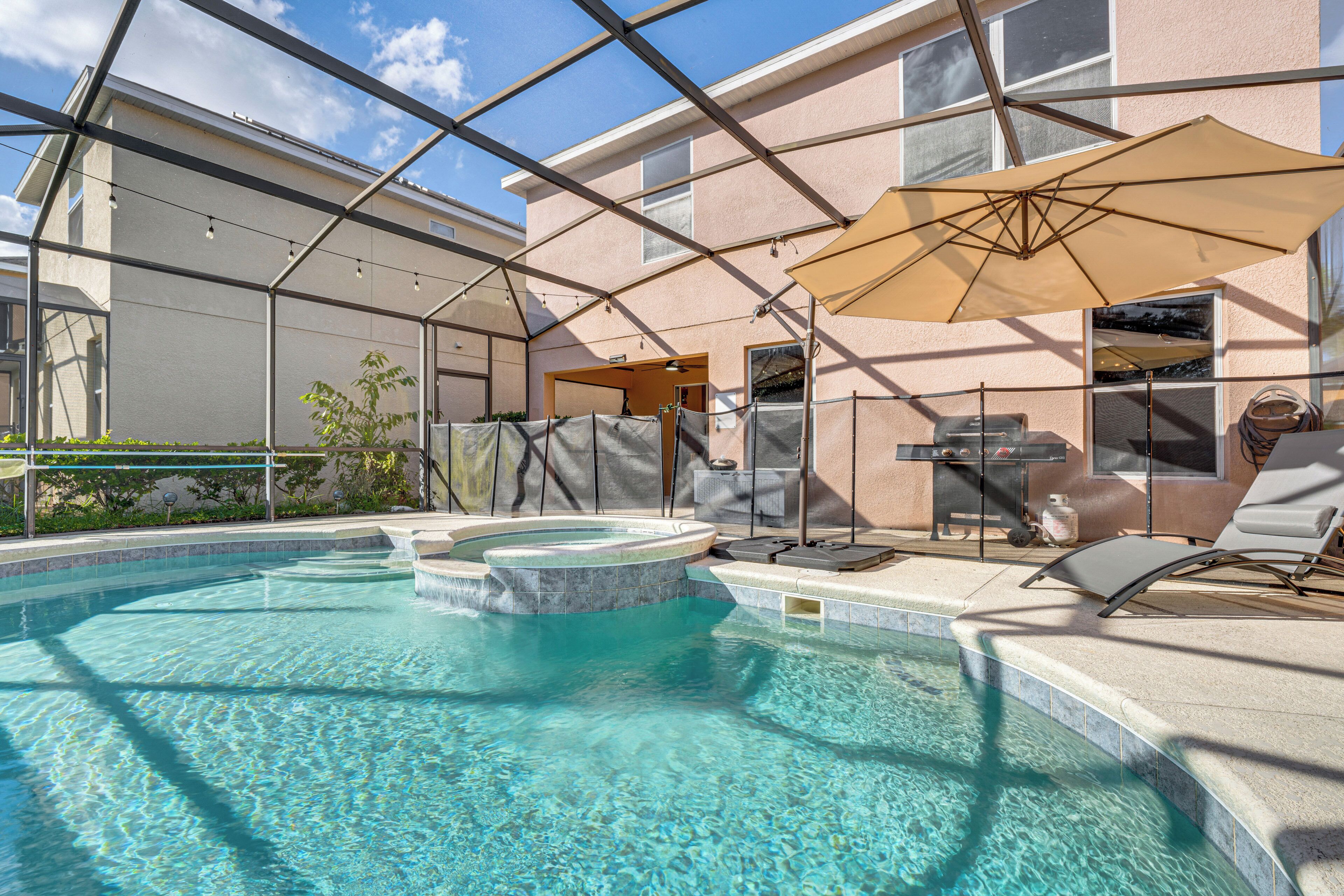 Una piscina con hidromasaje, sillas de descanso y una sombrilla.