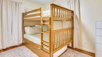 Een stapelbed met houten frame, witte beddengoed en een rug met een patroon.