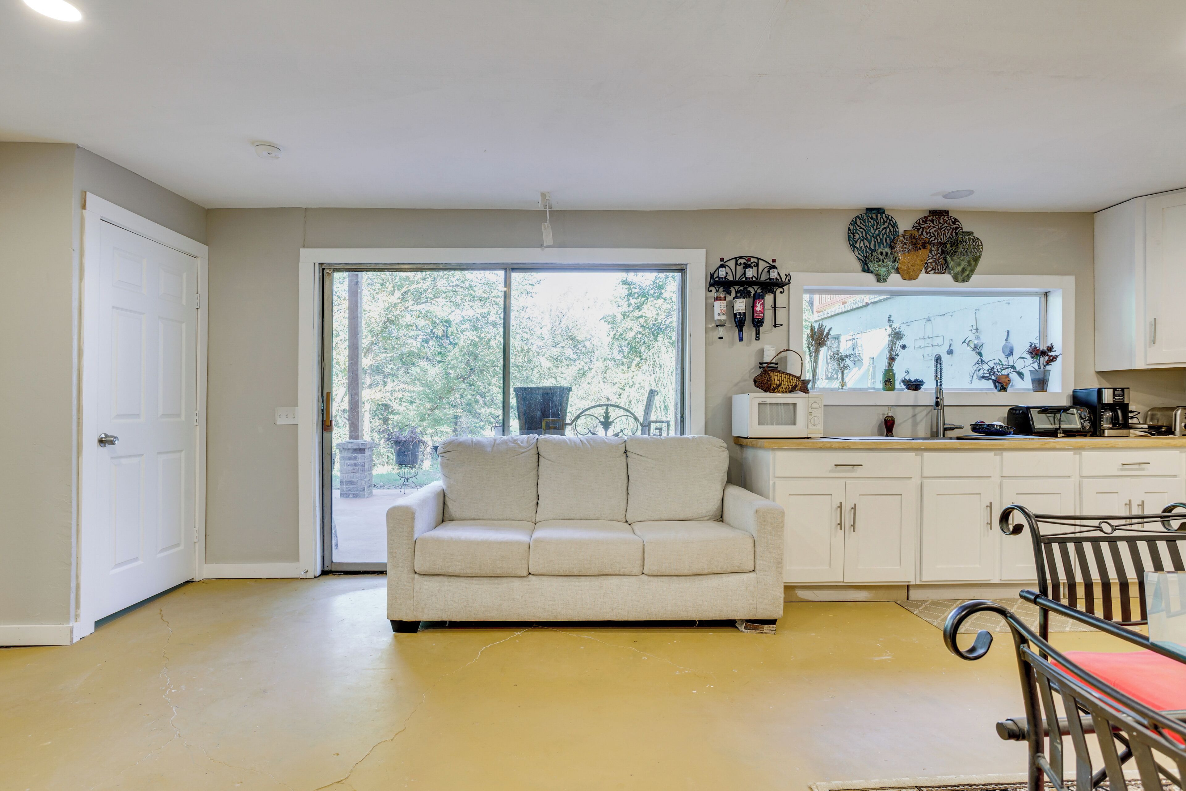 A kitchen with a white countertop, a white refrigerator, and a window with a view of trees.