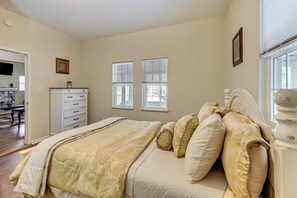 A bedroom with a bed, a dresser, and two windows.