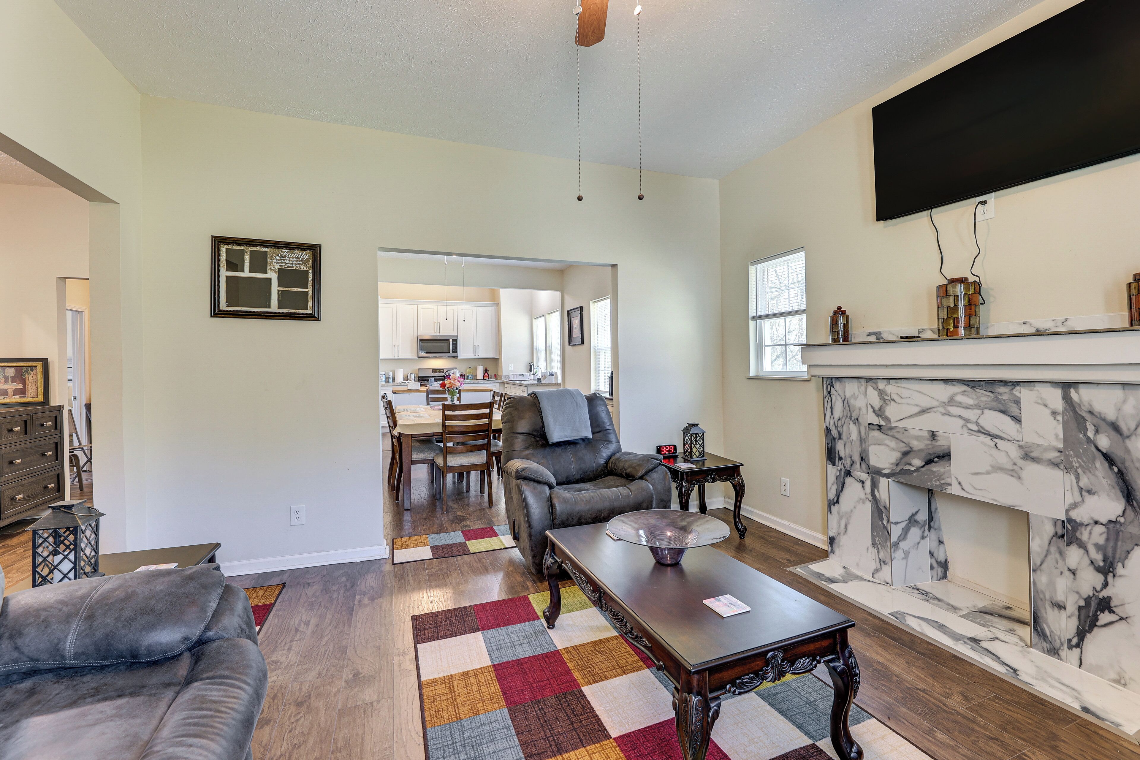A spacious living room with a fireplace, a dining area, and a kitchen in the background.
