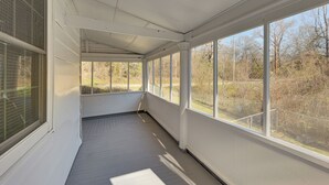 A covered porch with large windows and a wooden floor. - 'Doris & Susan's Place' - Historic Tuskegee Home (Tuskegee)