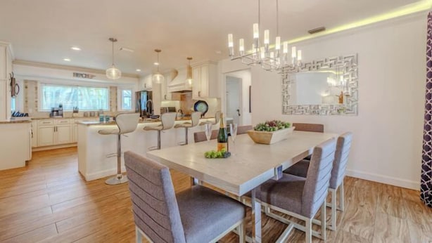 A modern kitchen with white cabinets, a central island, and pendant lighting. - Cape Coastal (Cape Coral)