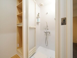Ein kleiner, abgeschlossener Duschbereich mit Handbrause, Handtuchhalter und Toilette.
