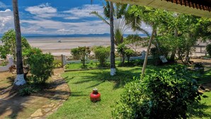 Un espacio al aire libre techado con vista a una playa y palmeras.