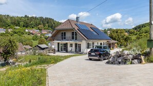 Uma casa com entrada para carros, painéis solares e um carro estacionado na frente.