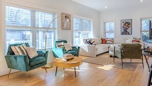 A spacious living room with a green armchair, a white sofa, and a round coffee table. - Spacious 6BR/5BA - Near DC & Pentagon (Arlington)