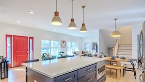 A spacious kitchen with a large island, pendant lights, and a red door. - Spacious 6BR/5BA - Near DC & Pentagon (Arlington)