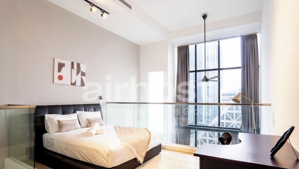 Quarto moderno com cama, escrivaninha e uma janela grande.