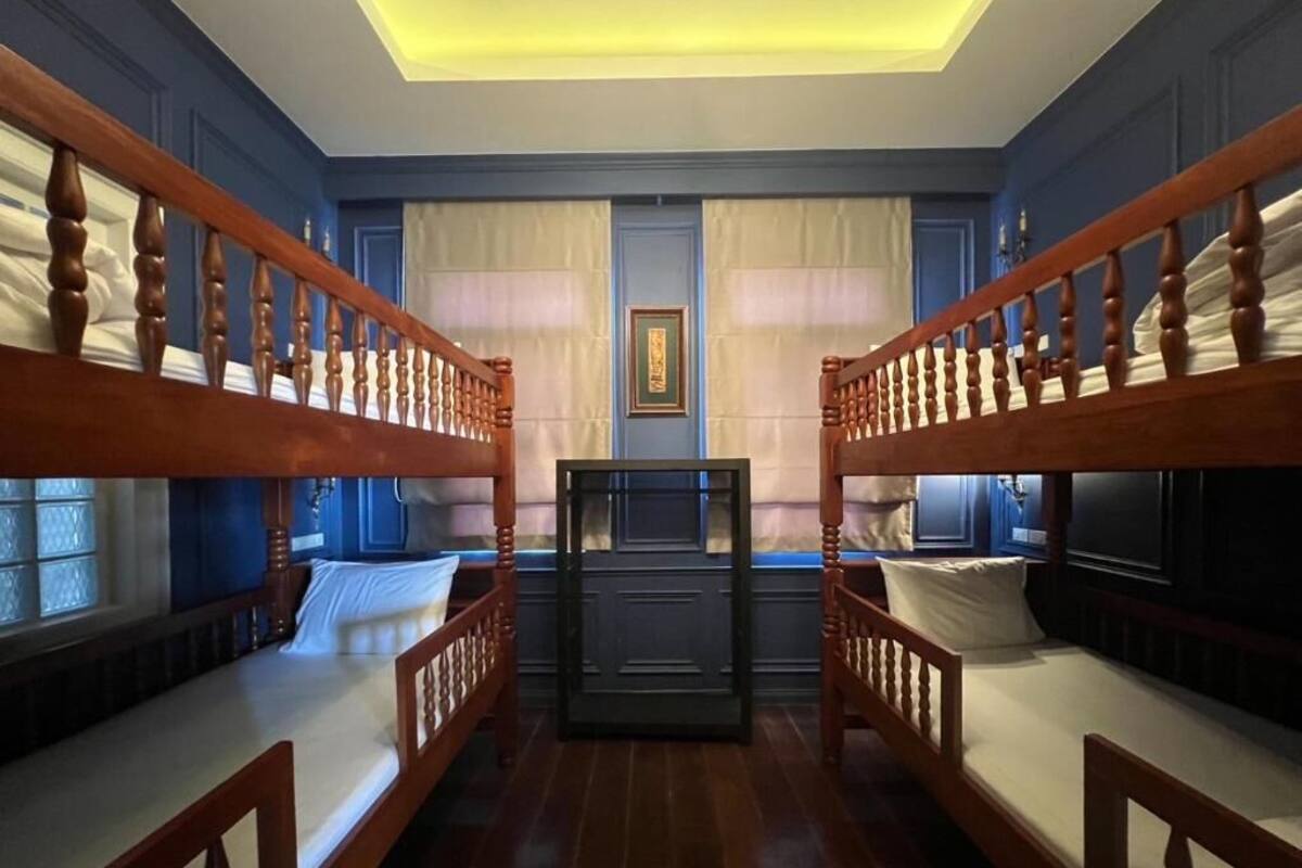 A room with bunk beds, a central desk, and a window with curtains.
