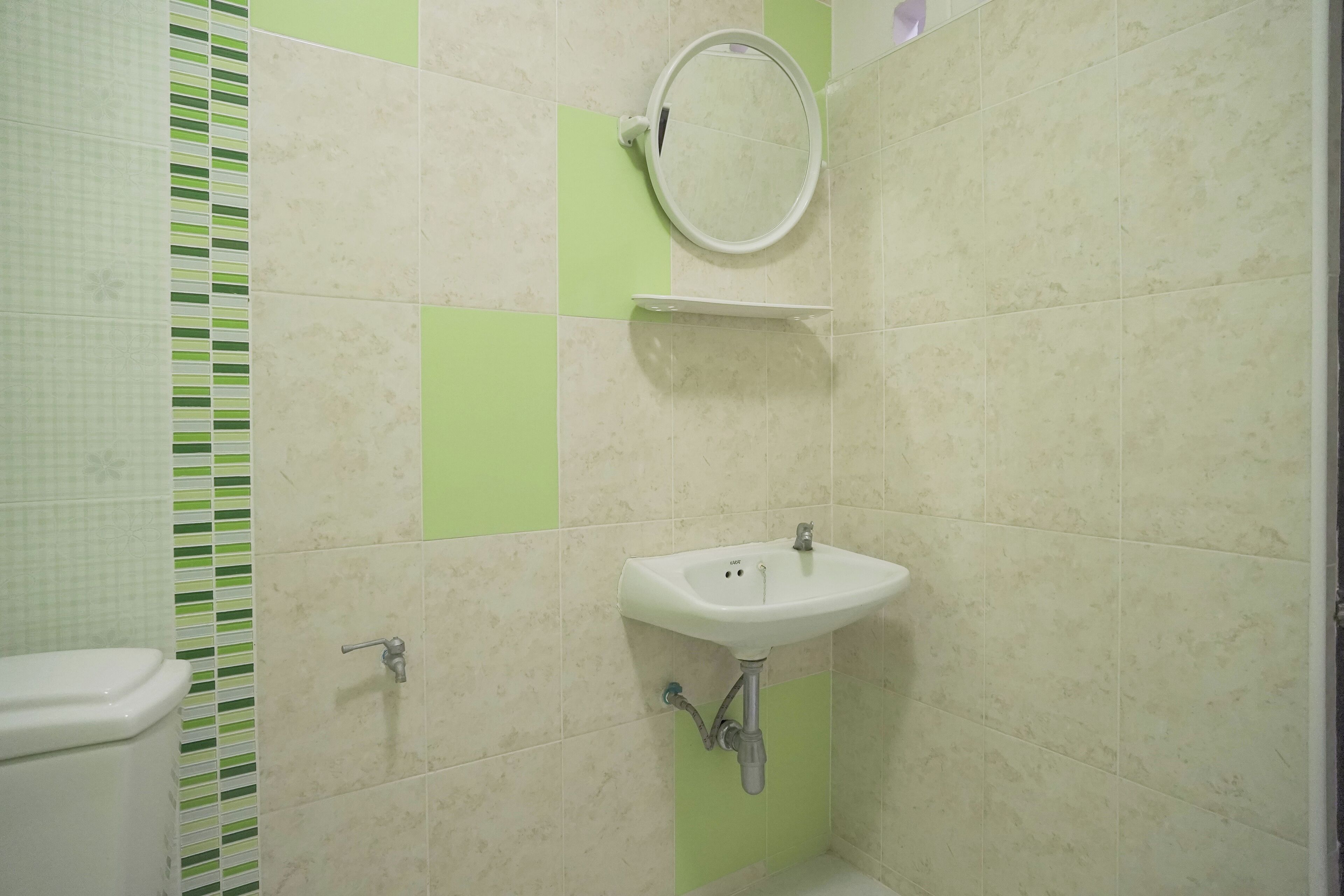 A bathroom with a toilet, sink, and mirror.