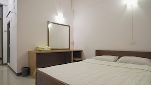A bedroom with a bed, a bedside table, a mirror, and a wall-mounted light fixture. - Suriyart Hotel (Ubon Ratchathani)