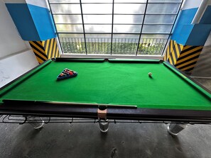 Ein Billardtisch mit grüner Spielbahn, einer blauen weißen Kugel und einem Satz farbiger Kugeln.