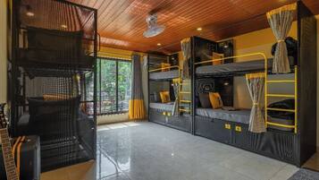A compact room with bunk beds, a woven chair, and a guitar.