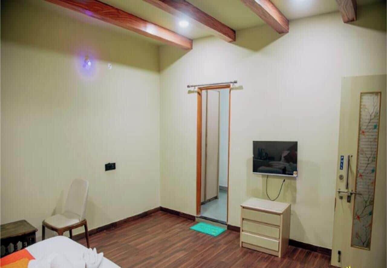 Habitación de hotel con techo de madera, una cama, una silla, un televisor, un armario y una puerta con un mapa.