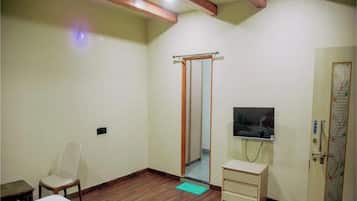 Habitación de hotel con techo de madera, una cama, una silla, un televisor, un armario y una puerta con un mapa.