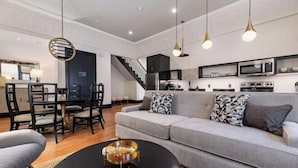 Ein modernes Wohnzimmer mit grauem Sofa, schwarzem Couchtisch und Pendelleuchten.