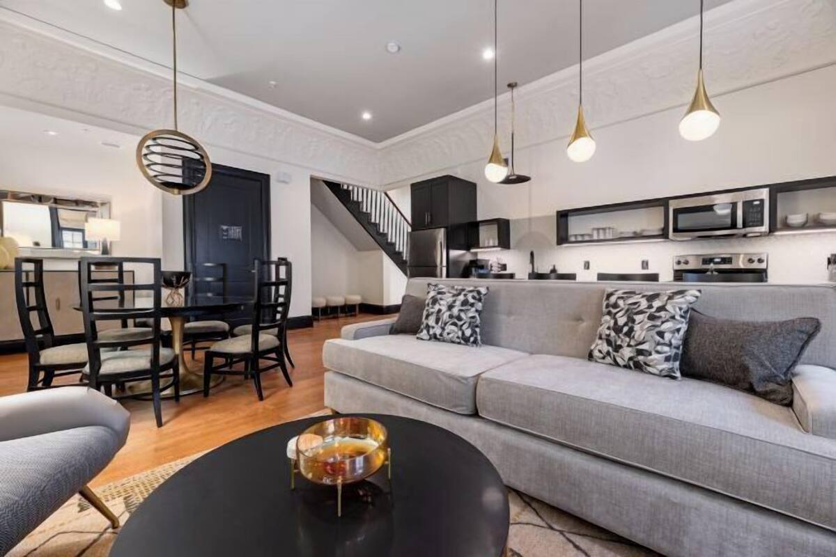 A modern living room with a grey sofa, black coffee table, and pendant lights.