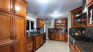 A spacious kitchen with wooden cabinets, a black countertop, and a stainless steel stove. - Cozy Corner on Carson (Burney)