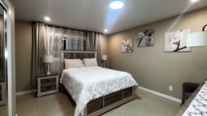 A bedroom with a bed, nightstands, a dresser, and wall art. - Cozy Corner on Carson (Burney)