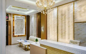 A hotel reception area with a marble wall, a chandelier, and a reception desk. - Hotel Holiday Dreamz (Amritsar)