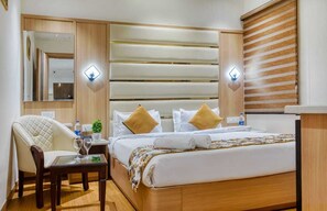 Una camera d'albergo con un letto, comodini, una sedia e un tavolino con una pianta e dei bicchieri.