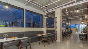 A modern dining area with high ceilings, large windows, and contemporary lighting fixtures. - The Hosteller Hyderabad HITEC City (Hyderabad)